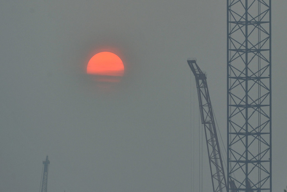 2014年10月08日，一轮初升的太阳在辽宁省大连市雾蒙蒙的天空中显得格外红。